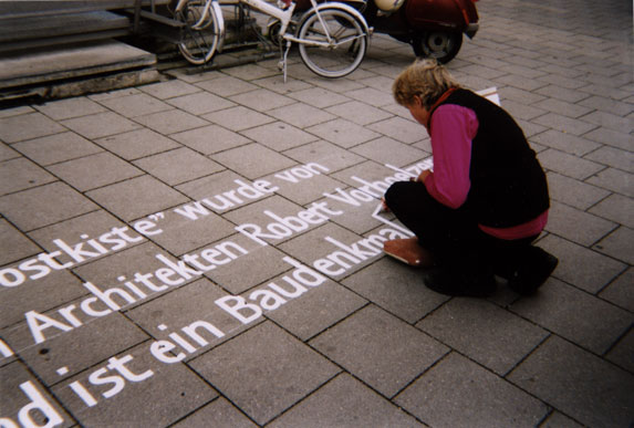 Irmgard Bauer bei der Beschriftung eines Gehwegs mit Text zu einem Baudenkmal